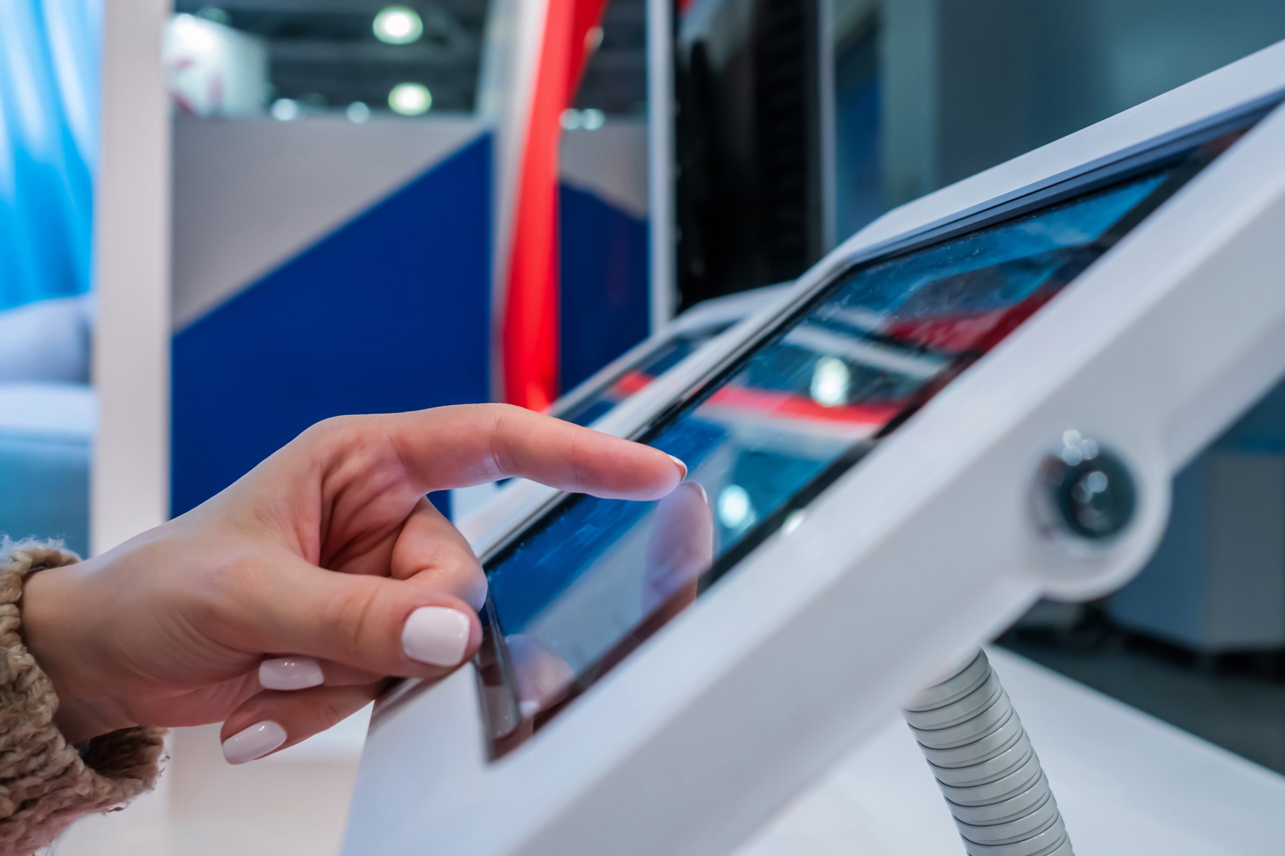 Woman hand using touchscreen display of floor standing white tablet kiosk